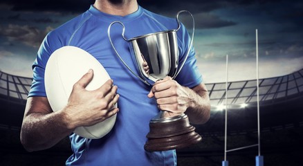 Wall Mural - Composite image of rugby player holding trophy and ball