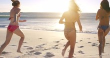 Young Women Running Into Ocean At Sunset In Slow Motion Playing In Waves On Tropical Beach