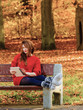© Voyagerix - Woman in autumn park using tablet computer reading.