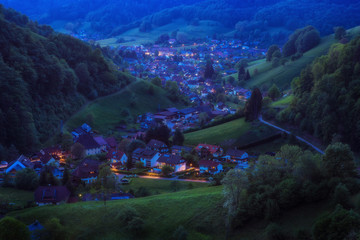 Wall Mural - Scenic countryside landscape with beautiful mountain village in late evening. Germany, Black forest, Muenstertal. Aerial panorama.