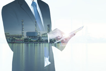 Double exposure of businessman with oil refinery industry