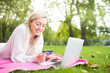 A woman using credit card shopping online with a laptop in the park
