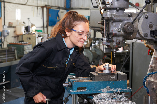 Fotografie, Obraz Female Apprentice Engineer Working On Drill In Factory