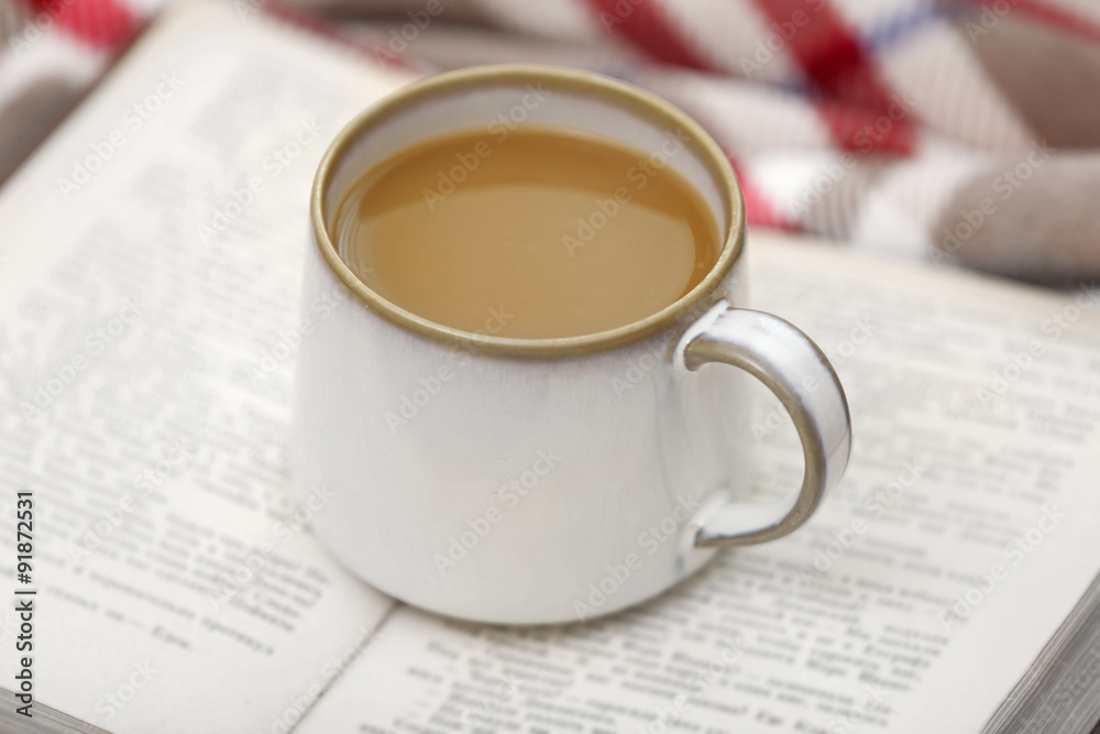 Cup of coffee with book on sofa in living room