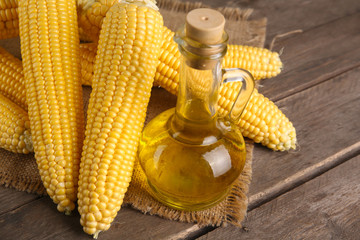 Wall Mural - Fresh corn with bottle of oil on table close up