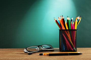 Sticker - Metal holder with crayons and glasses on desk on green chalkboard background