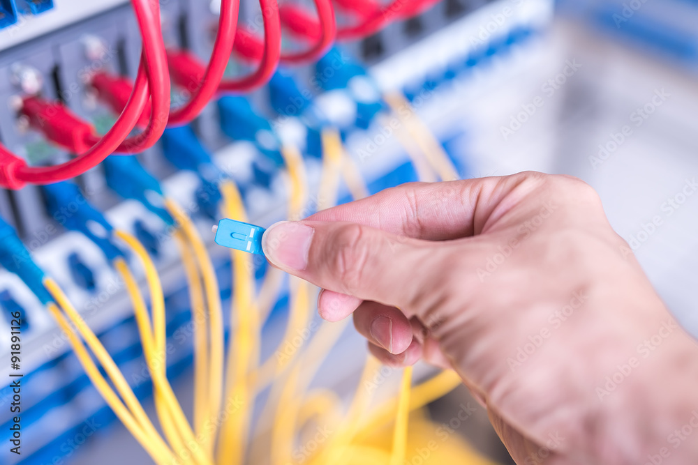 man working in network server room with fiber optic hub for digi