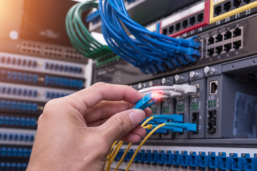 Wall Mural - man working in network server room with fiber optic hub for digi