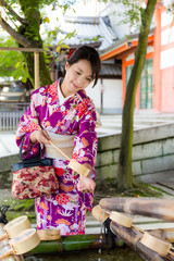 Canvas Print - Young japanese woman use of the bamboo ladle in water fountain