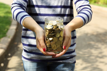 Poster - Woman holding money jar with coins outdoors