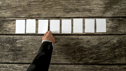 Wall Mural - overhead view of male hand placing eight blank white cards in a