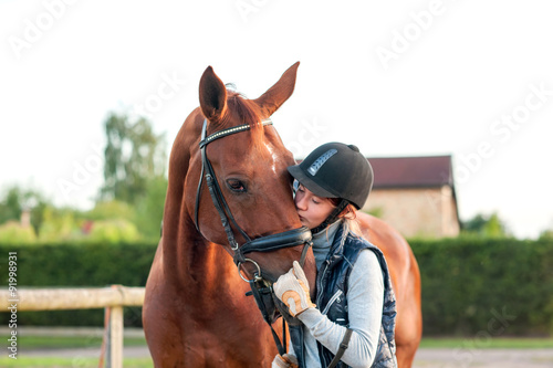 Fotografía Young teenage girl equestrian kissing her chestnut horse.