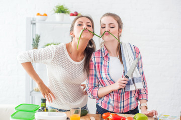 Wall Mural - Women preparing healthy food playing with vegetables in kitchen