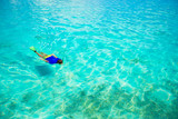 Fototapeta Do akwarium - Young man snorkeling in clear tropical turquoise waters
