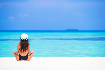 Young woman sitting in yoga position during tropical vacation