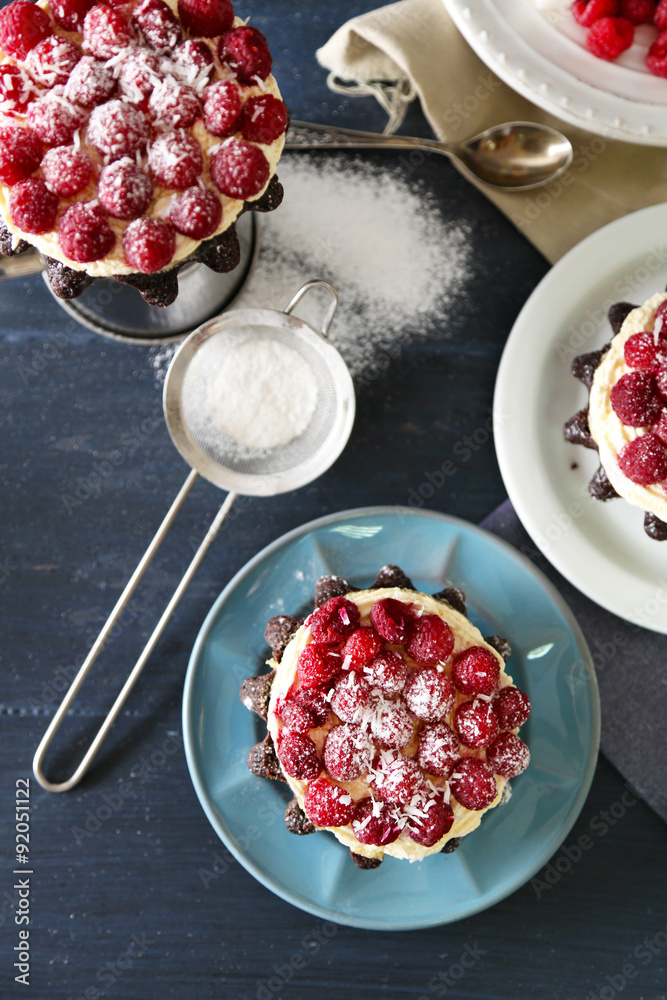 Sweet cakes with raspberries on color wooden background