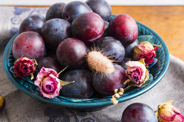 Wall Mural - Purple plums in a green plate on a wooden table