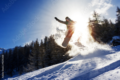 Cuadros en Lienzo Poderosa imagen de un snowboarder que salta sobre un trampolín en el polvo fuera