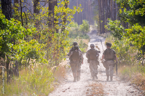 Fotografía Group of armed soldiers on the road in forest
