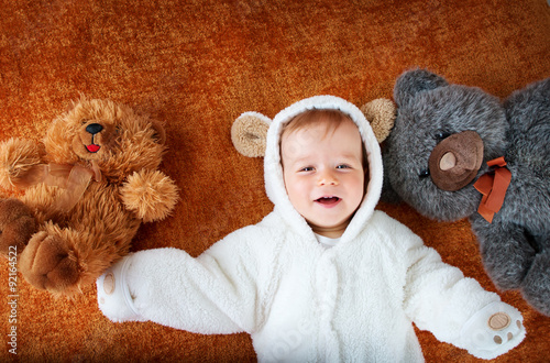 Little baby in bear costume with plush toys Poster