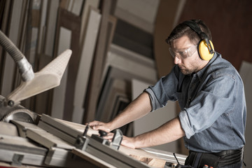 Carpenter cutting wooden plank