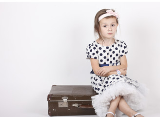 Little girl sitting on an old suitcase