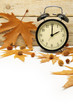 Autumn Time Change / Fall Back / Maple Leaves and an Alarm Clock on a Wooden Background