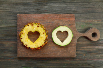 Poster - Fruits slices with cut in shape of heart on wooden background