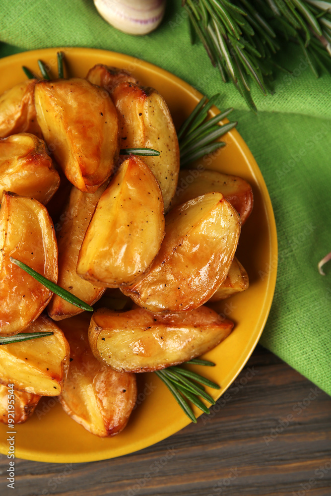 Baked potato wedges on wooden table, top view