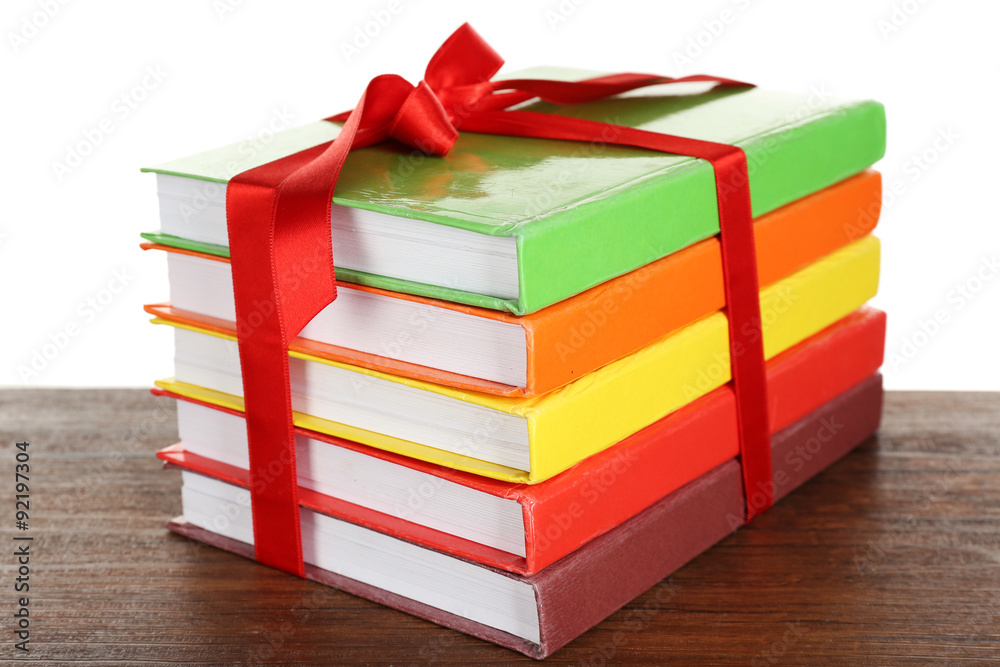 Stack of books with ribbon on light background