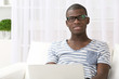 © Africa Studio - Handsome African American man sitting with laptop on sofa in room