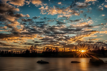 Colorful and cloudy fall sunset by a lake in the forest with smoot water thanks to a long exposure