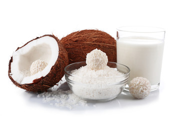 Candies in coconut flakes, glass of milk and fresh coconut isolated on white