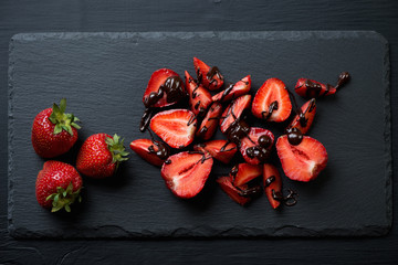 Wall Mural - Ripe sliced strawberries with chocolate on a stone slate dish