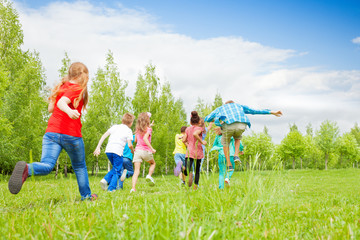 view from behind of kids running through field
