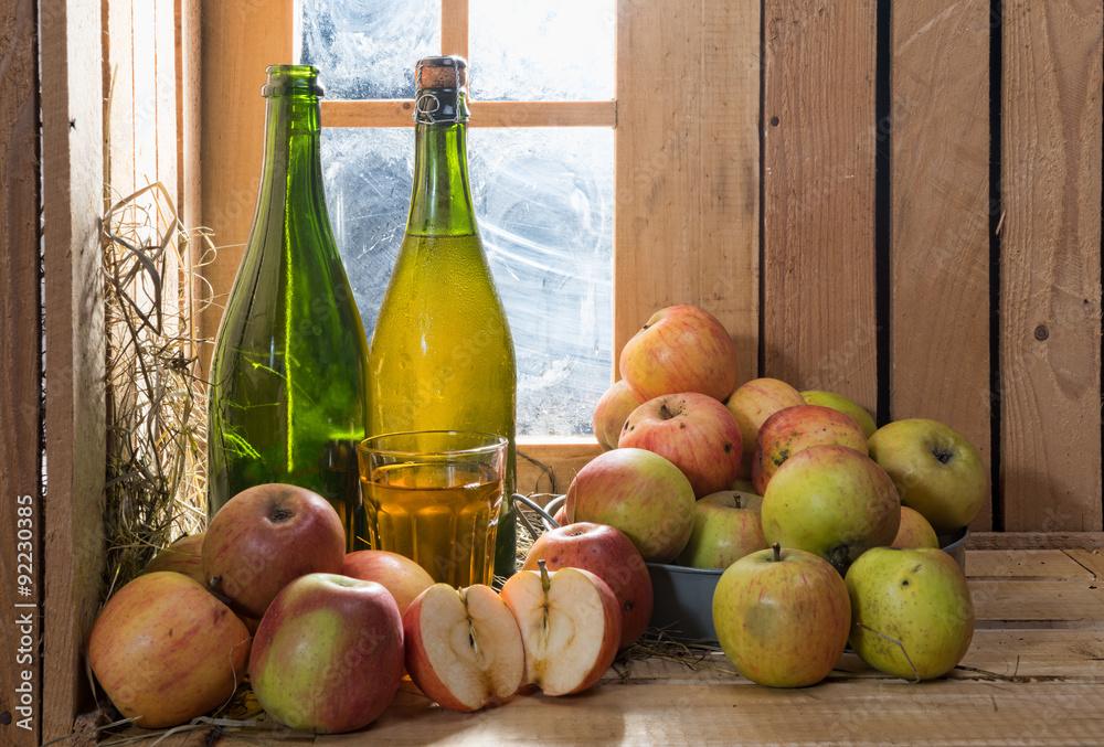 bottles and glass of cider with apples