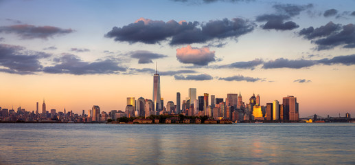 Fototapete - Lower Manhattan skyscrapers before sunset with One World Trade Center. Ellis Island appears in front of New York City’s Financial District.