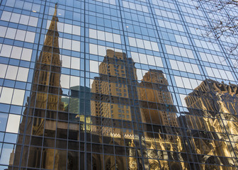 Reflection of old brown stone church and building in the glass of tall modern business building at New York Manhattan