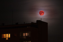 Red Full Moon In Red Color Also Called Bloodmoon On The Background Of Building.