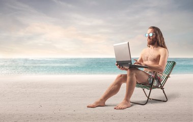 Surfer using a laptop at the beach