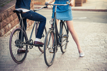 Young couple sitting on a bicycle opposite the city 