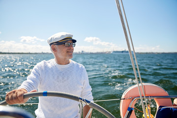 Poster - senior man at helm on boat or yacht sailing in sea