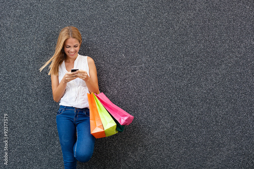 Fotografía Happy young woman typing a message the phone after shopping