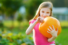 Cute Little Girl Holding A Pumpkin