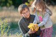Autumn park outdoors portrait of sibling children examining light yellow armful of leaves