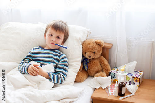 Fotografia Sick child boy lying in bed with a fever, resting
