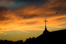 Metal Cross Silhouette On A Church Roof At Sunset, Over An Orang