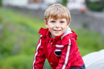 Wall Mural - Portrait of little schoolboy outdoors on rainy day