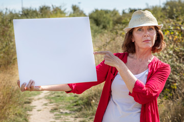 beautiful mature woman alerting people with banner in sunny outdoors