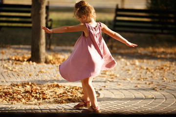 Full length portrait of a little girl dancing in the park a warm